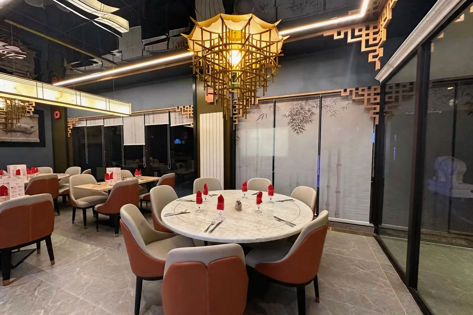 A table set with red napkins, beneath a golden pagoda-shaped chandelier, evening mood