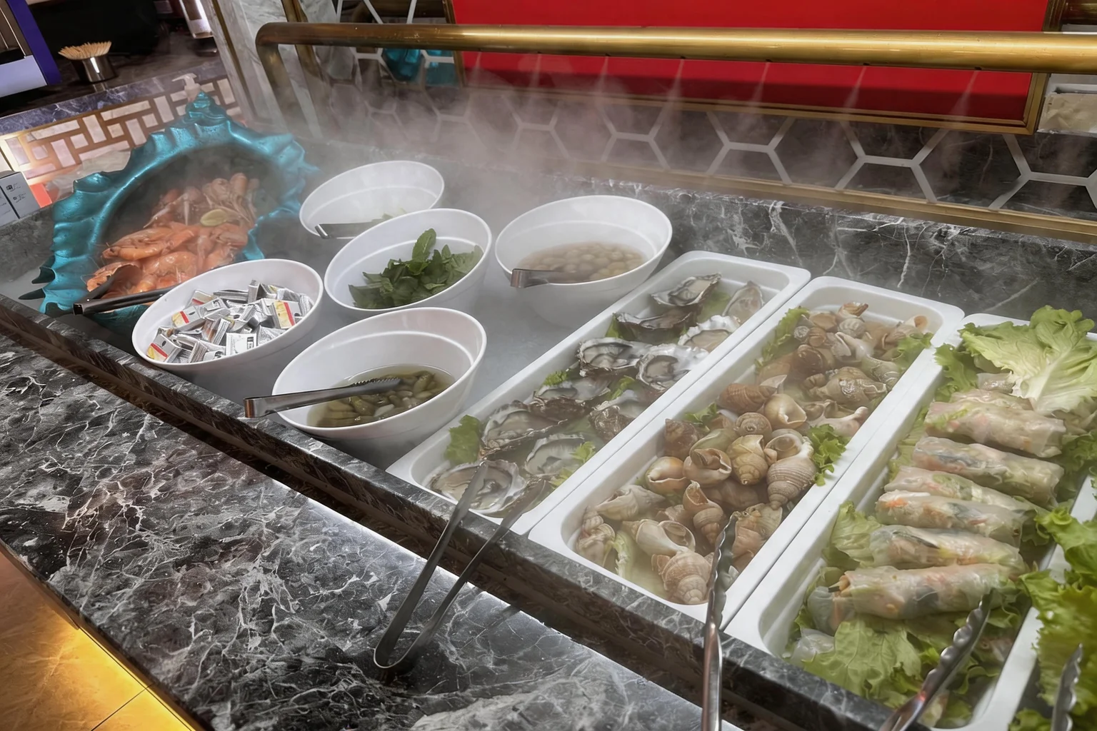 The buffet's seafood bar with oysters, whelks and prawns on ice, steam rising above the trays