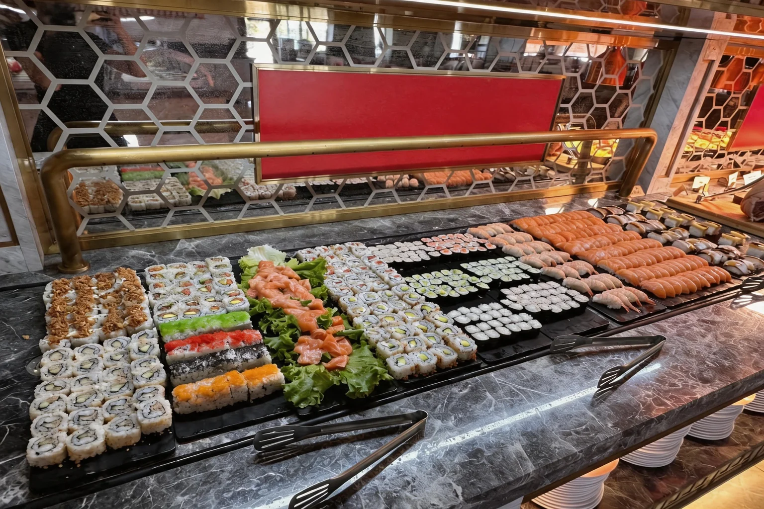 Trays of sushi, maki and salmon sashimi lined up on the buffet counter