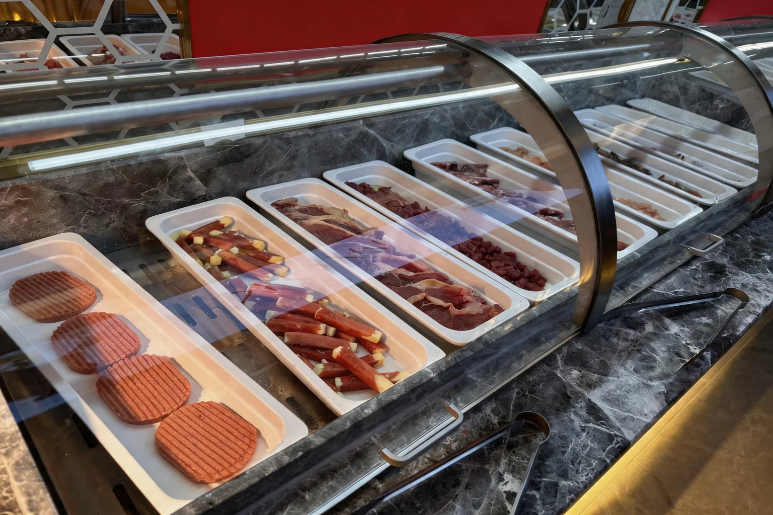 Trays of assorted raw meats displayed under glass on the buffet, ready for the grill